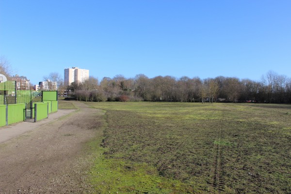 Un parc accueillant des équipements sportifs, avec des bosquets denses en son centre.